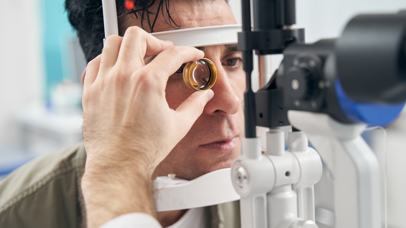 Patient at the slit lamp while the examiner holds a contact lens to the eye